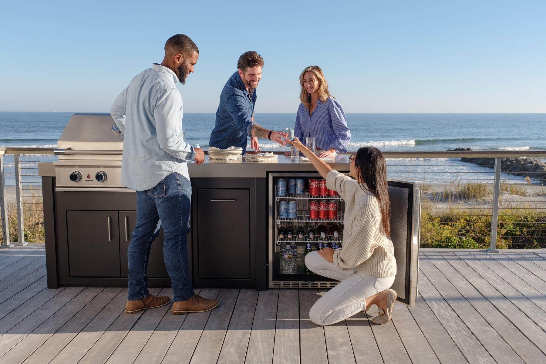 Couple grilling at a Stono outdoor kitchen island with ocean waves in the background, showing the grill, counter run and storage as one unit.